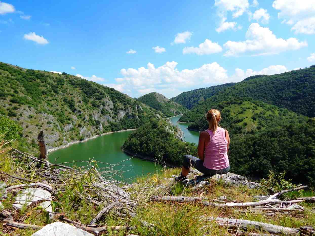 devojka sedi na steni okrenuta ledjima i posmatra reku i meandre, Uvac, uklješteni meandri